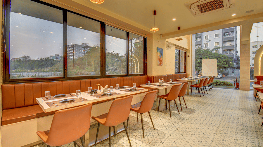 Dining area with large windows, natural light, and rows of tables and chairs at VITS Select Nashik Hotels & Resorts.
