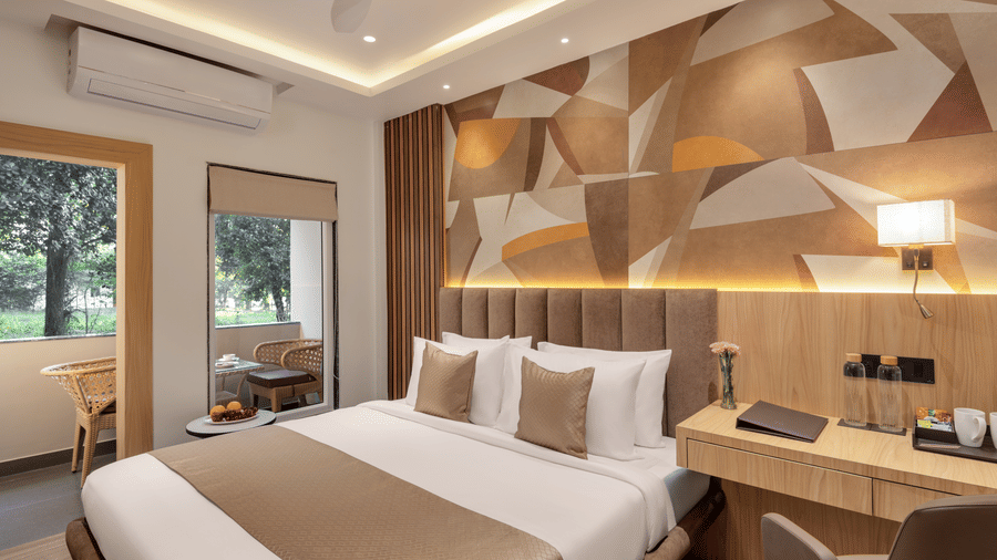 A hotel bedroom with a large double bed, bedside tables and lamps on either side, and a decorative headboard wall | Voyage Eastin Suites