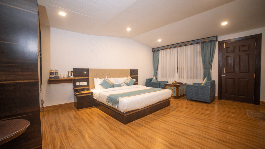 Elegant guest room at Voyage Glenz Resort with plush bedding, sofa, and warm lighting.