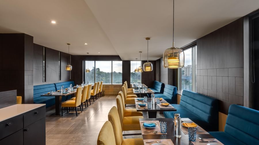 Restaurant interior at Voyage Milestone Hotel and Banquet with blue seating and warm lighting.