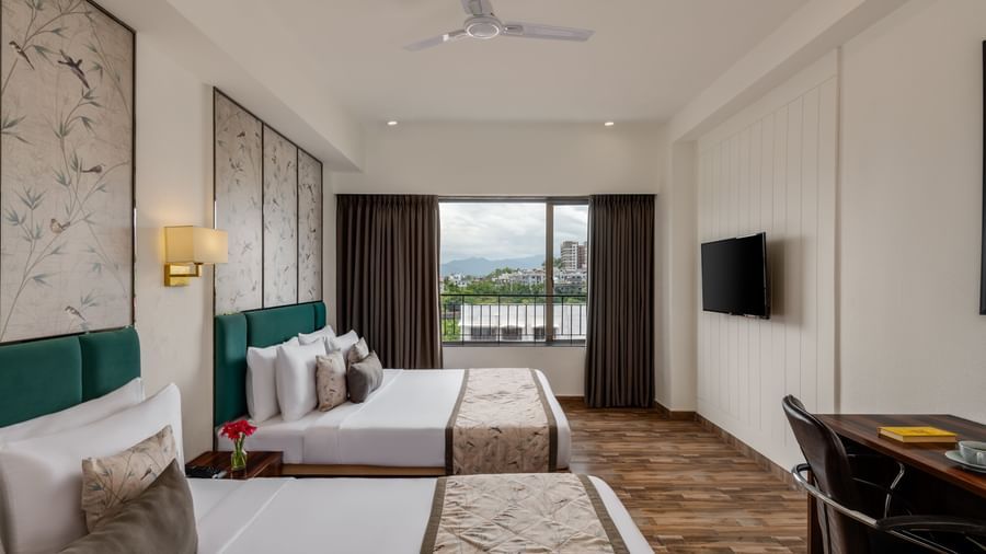 Bright guest room at Voyage Milestone Hotel and Banquet with twin beds and balcony view.