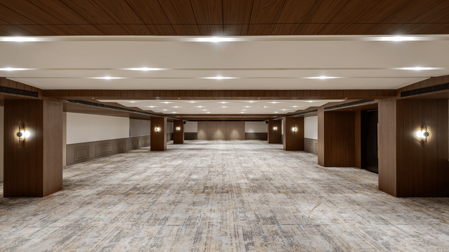An empty hall of Aura at Voyage Milestone Hotel And Banquet with patterned carpet under warm lighting
