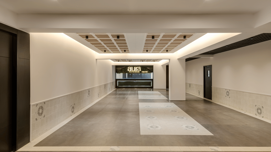 A patterned floor leading to Aura Kitchen shown with an empty counter under warm lighting at Voyage Milestone Hotel And Banquet