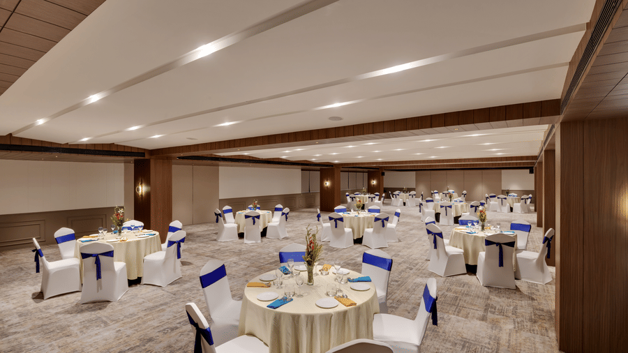 Aura at Voyage Milestone Hotel And Banquet featuring chairs arranged around round tables with cutlery placed on each of them