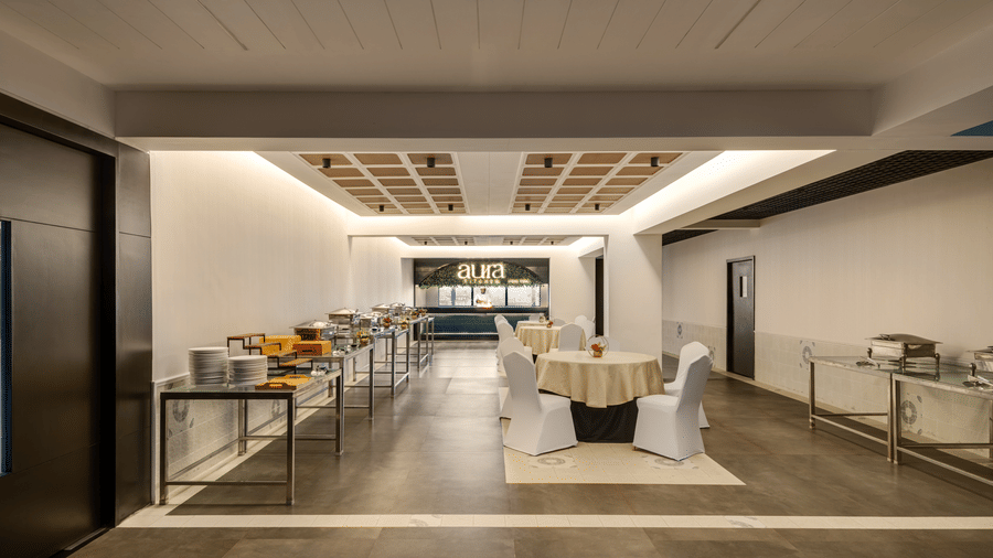 Seating arrangement next to the buffet table at Aura, Voyage Milestone Hotel And Banquet with the kitchen counter in the background