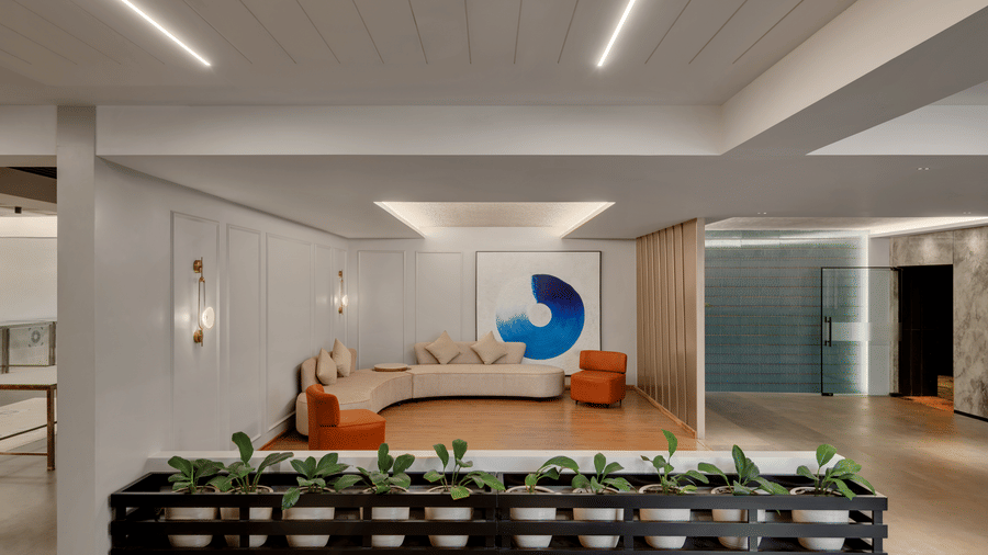 A seating area at Aura featuring an L-shaped sofa and couches on both sides and planters lined up in a distance at Voyage Milestone Hotel And Banquet