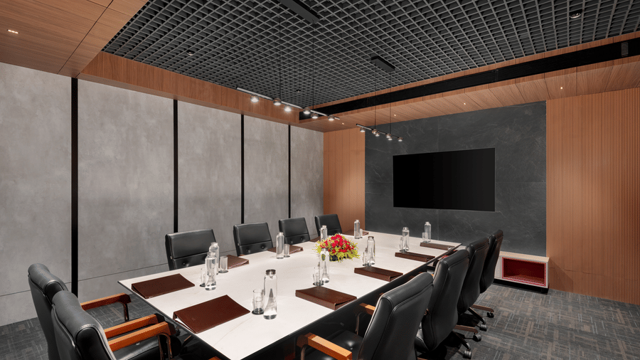 Boardroom at Voyage Milestone Hotel and Banquet featuring chairs arranged around a table with bottles of water and files and flower vase on it with 2 chairs facing the monitor on the wall