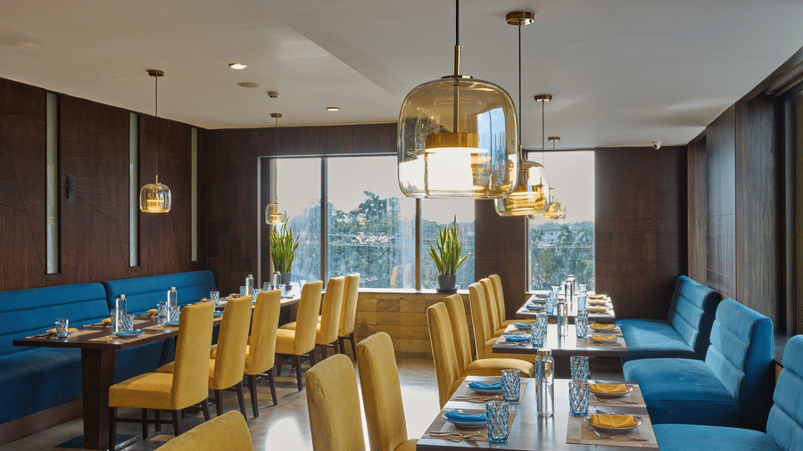 Fine dining area with velvet seating and warm wooden accents in Fine dining area with blue velvet seating and warm wooden accents in Voyage milestone hotel.