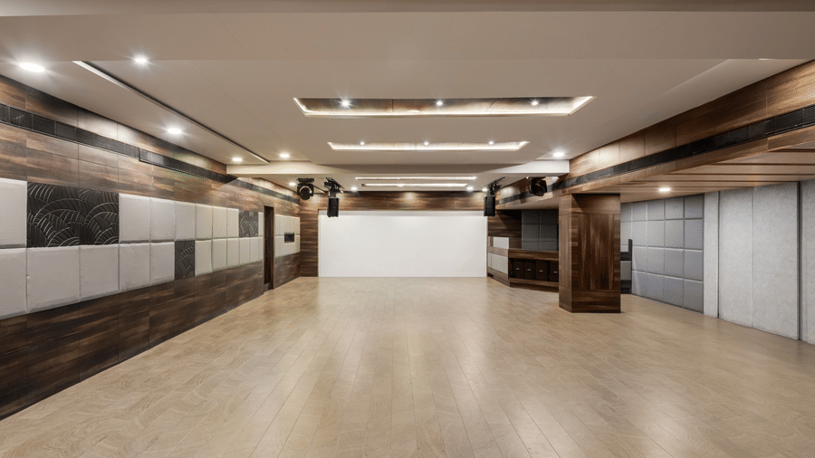 An empty Spectrum hall at Voyage Milestone Hotel And Banquet under warm lighting and patterned walls and light equipment hanging from the ceiling
