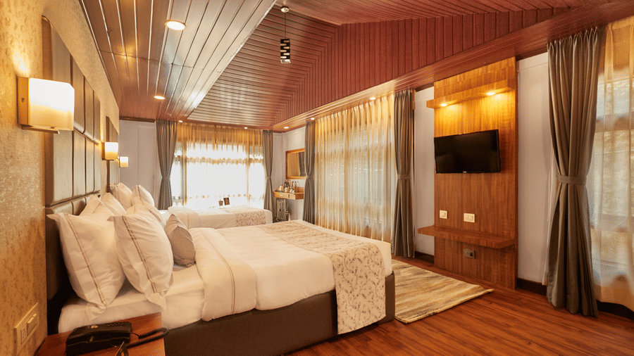 A room featuring wood-panelled ceilings, wall-mounted TV, and large floor-to-ceiling curtains | Voyage Rodhi Resort