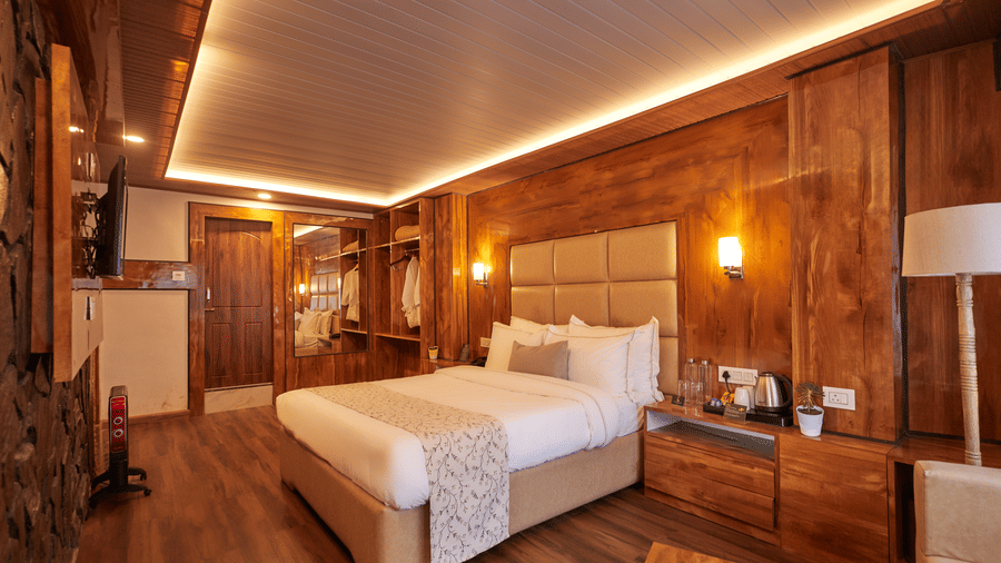 Warmly lit suite featuring wood panelling, a king size bed, and a sleek dressing area | Voyage Rodhi Resort