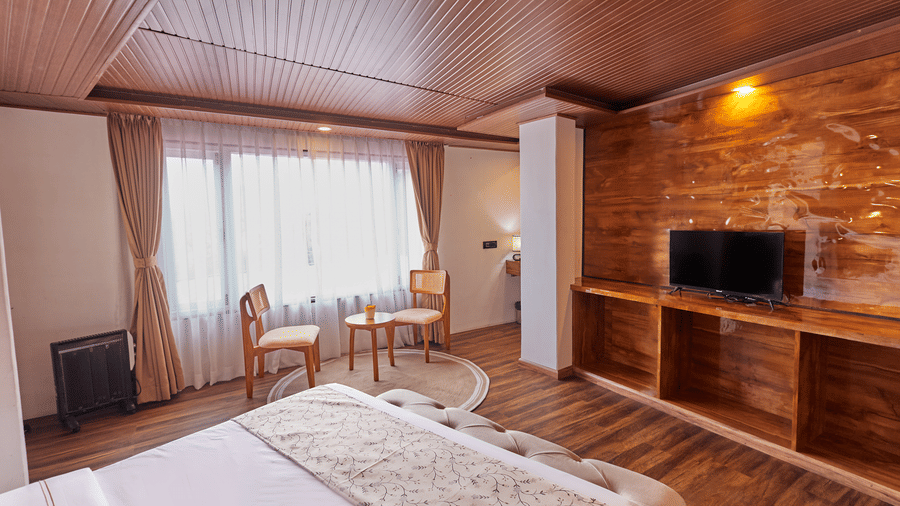High-angle shot of a hotel room with white linens, wooden built-ins, and a large window | Voyage Rodhi Resort