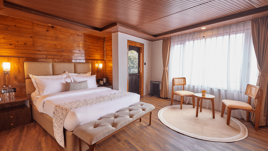 A spacious suite with polished timber floors, a seating area, and a large window | Voyage Rodhi Resort