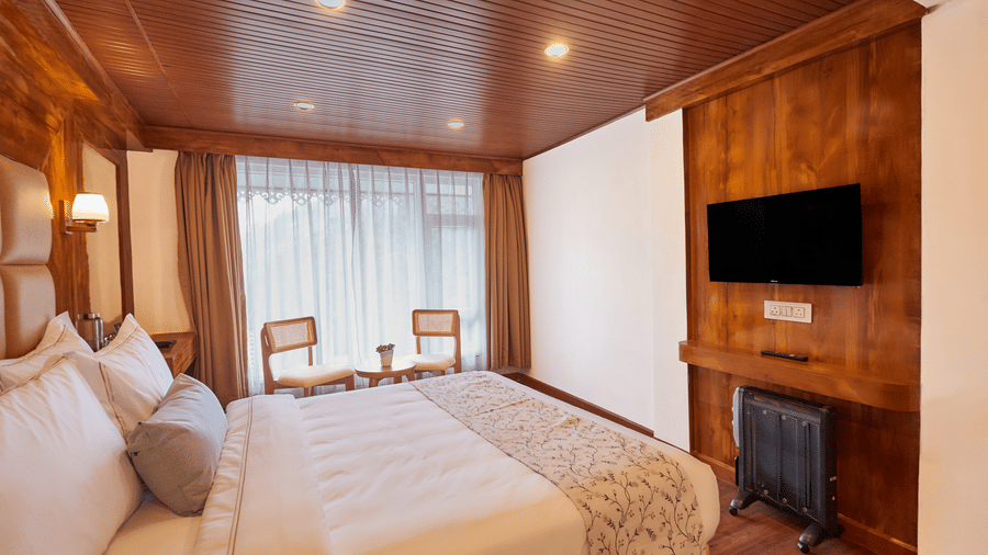 Spacious hotel room with white linens, wall-mounted TV, and large windows for natural light | Voyage Rodhi Resort