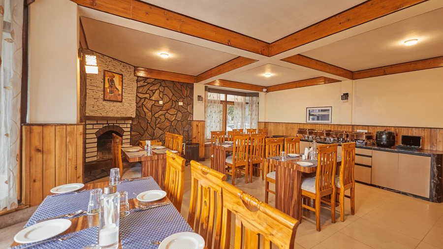 A dining space with a fireplace, set tables, and wooden wall panelling | Voyage Rodhi Resort
