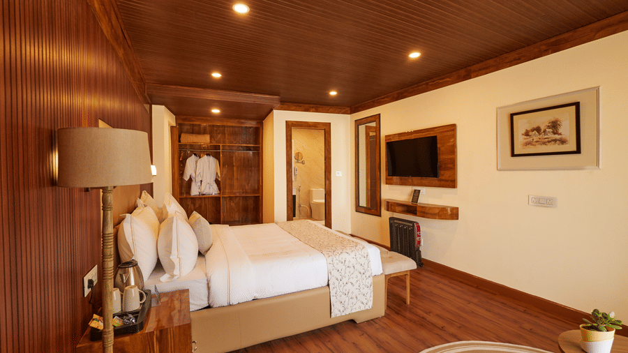 A hotel room with warm wood finishes, a workspace, and a large king bed | Voyage Rodhi Resort