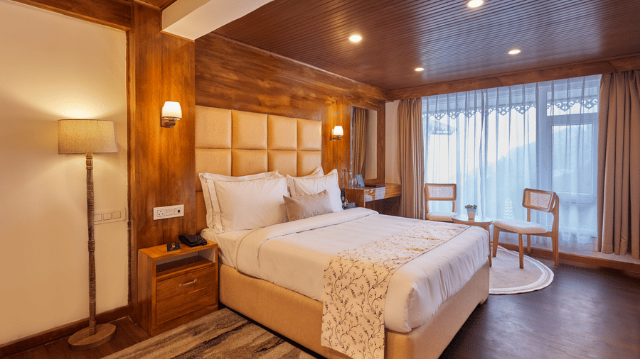 A hotel room with timber walls, a tall floor lamp, and a large window for natural light | Voyage Rodhi Resort