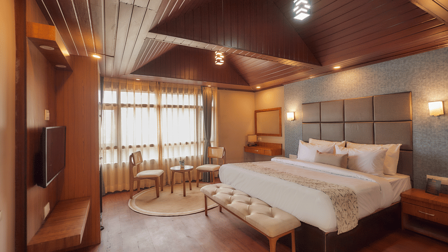 A spacious bedroom with an upholstered headboard, recessed lighting, and a dining set | Voyage Rodhi Resort