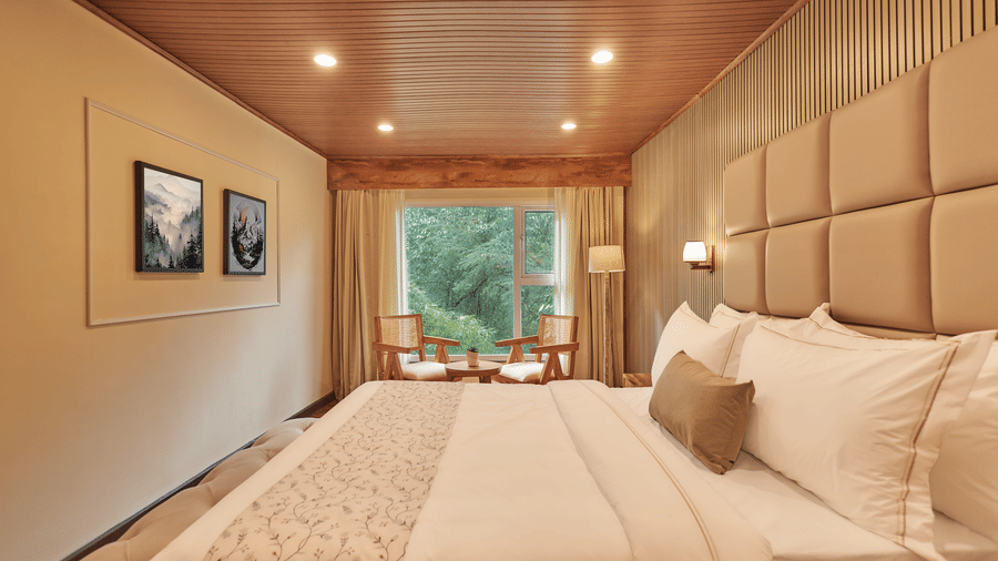 A suite with a large tufted headboard, bedside lighting, and lush green views | Voyage Rodhi Resort