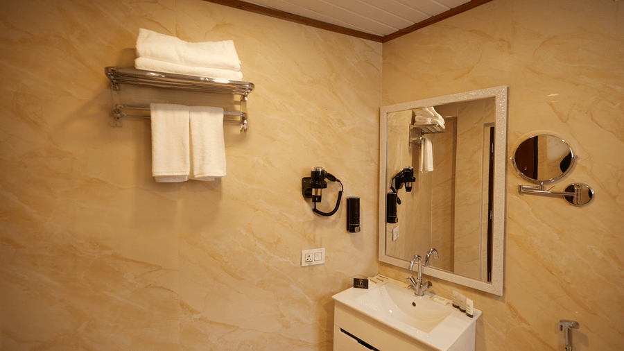 A bathroom featuring a white vanity unit, large mirror, and wall-mounted hairdryer | Voyage Rodhi Resort