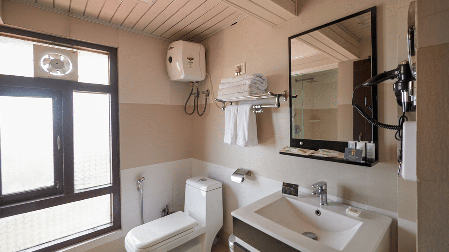 A bathroom with a modern toilet, white sink, and window for ventilation | Voyage Rodhi Resort