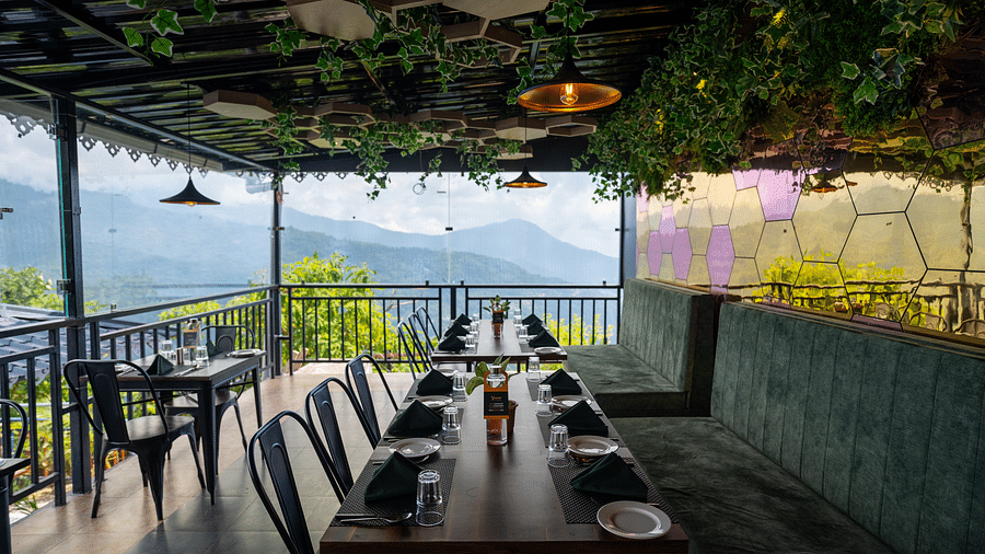 An outdoor dining area with a roof that is decorated with lights and leaves, offering scenic mountain views | Voyage The Royal Retreat, Gangtok
