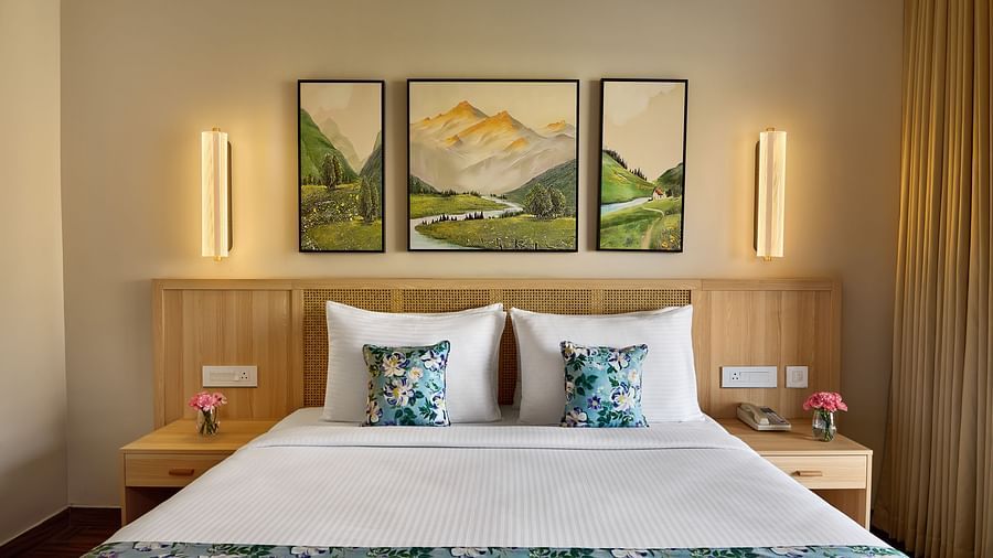 Cosy bedroom with a neatly made double bed, vibrant floral accents, modern lighting, and a triptych landscape painting above the headboard - Voyage The Solitaire Bliss.