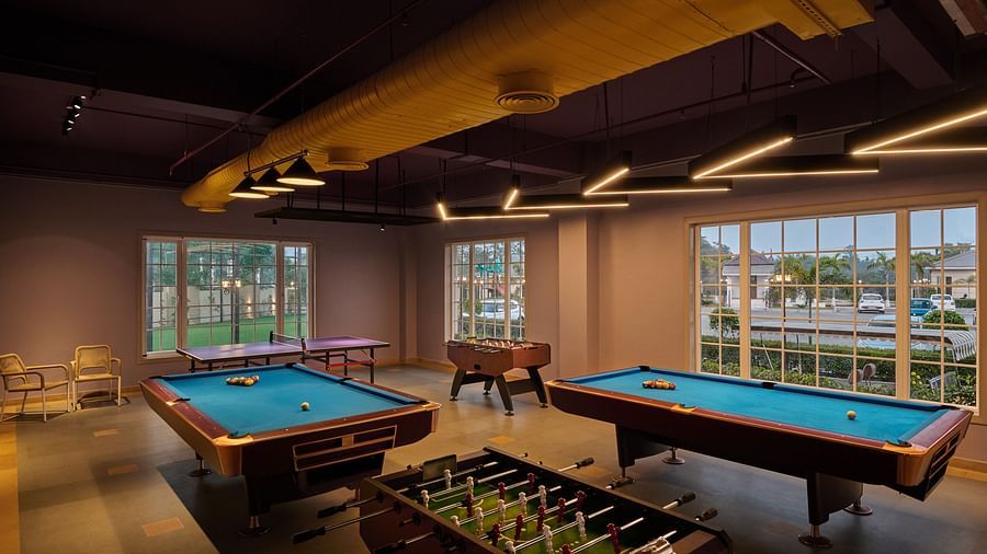 Indoor game room featuring two pool tables and a foosball table, with large windows allowing natural light to illuminate the stylish space - Voyage The Solitaire Bliss.