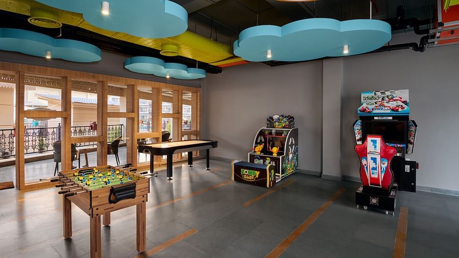 Colourful indoor game room with arcade machines, foosball tables, and playful ceiling decor shaped like clouds, featuring large windows and a polished floor - Voyage The Solitaire Bliss.