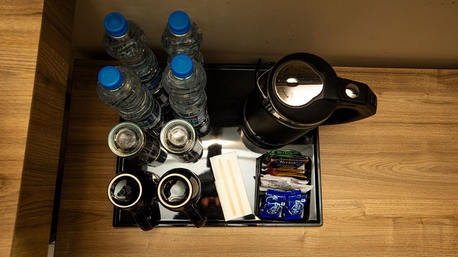 Two cups, water bottles, tea packets, and a kettle on a tray