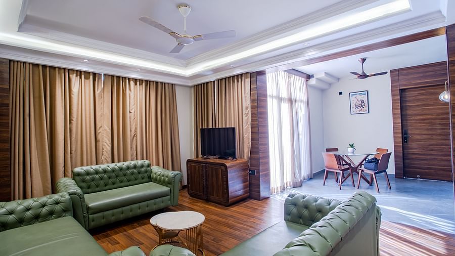 sofas with a table in centre and a tv on the side - Wedlock Greens Hotel Resorts Dhanbad