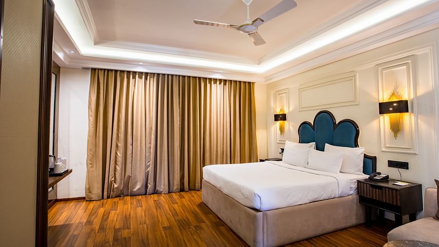 a double bed with side table and a sofa on the side inside one of the rooms - Wedlock Greens Hotel Resorts Dhanbad