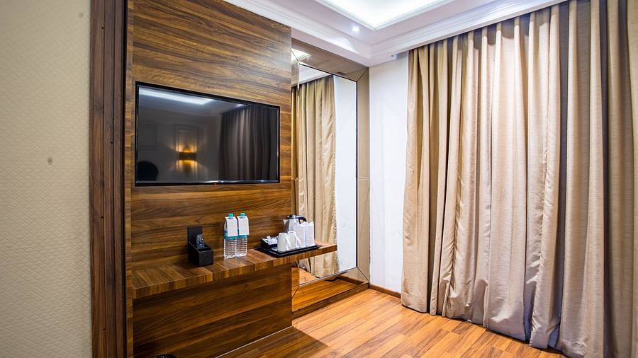 a tv wall mounted with other things kept on the shelf below it at our Dhanbad hotel rooms - Wedlock Greens Hotel Resorts Dhanbad