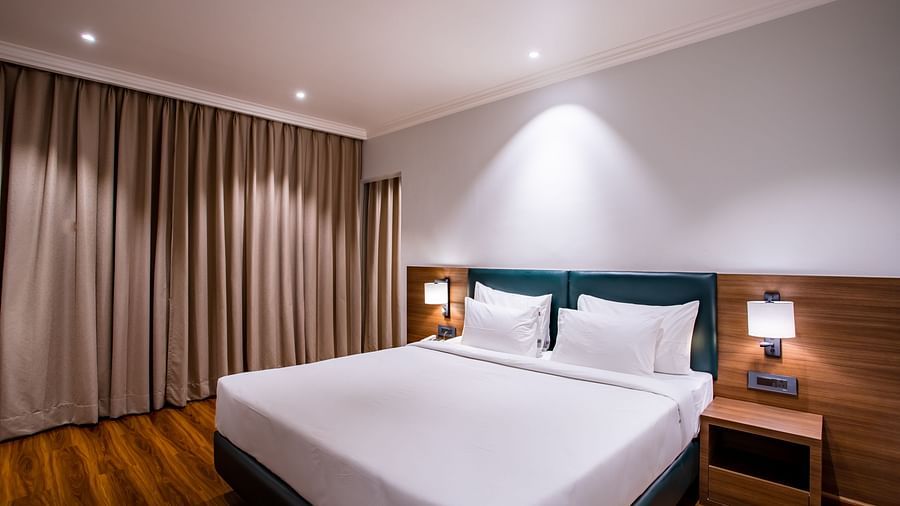 a double bed with side tables and lamps inside one of the rooms - Wedlock Greens Hotel Resorts Dhanbad