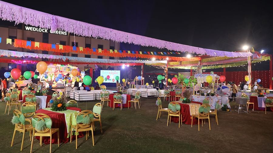 People gather in the outdoor venue, which is decorated for a celebration. - Wedlock Greens Hotel Resorts Dhanbad