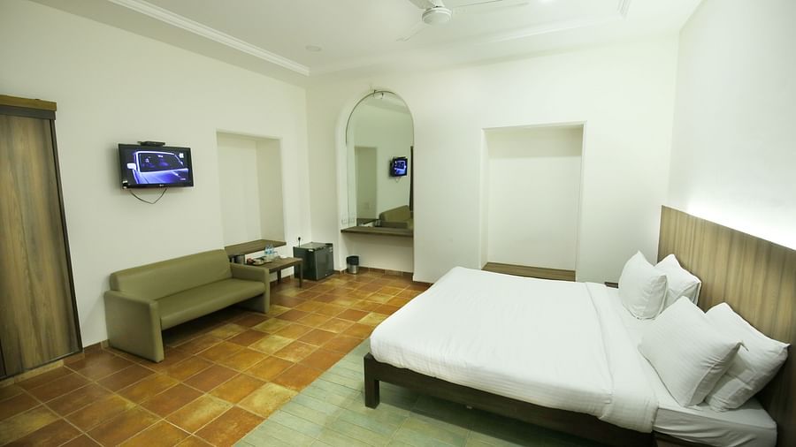 a king size bed facing the TV and sofa in the luxury cottage in Lonavala - Zara's Resort