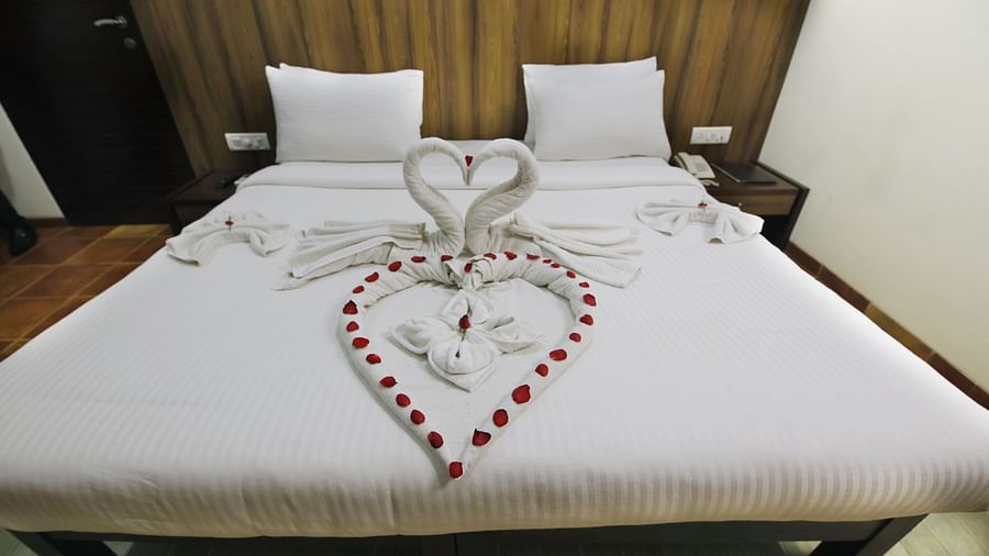 a king size bed with white sheets decorated with rose petals offered at the room - Zara's Resort