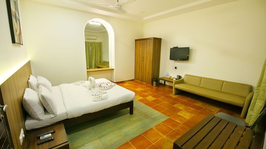 a king size bed facing a sofa offered at the luxury cottages in Lonavala
