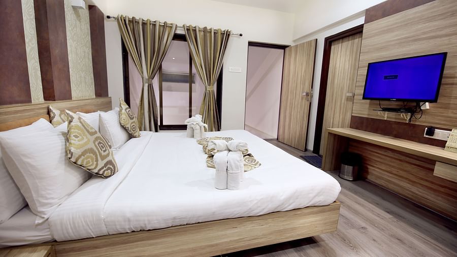 a king size bed facing the TV offered by the Penthouse room in Khandala -  Zara's Resort 1