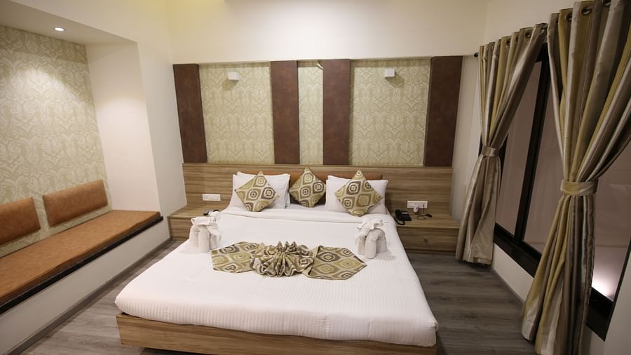 a king size bed facing the TV offered by the Penthouse room in Khandala -  Zara's Resort 2