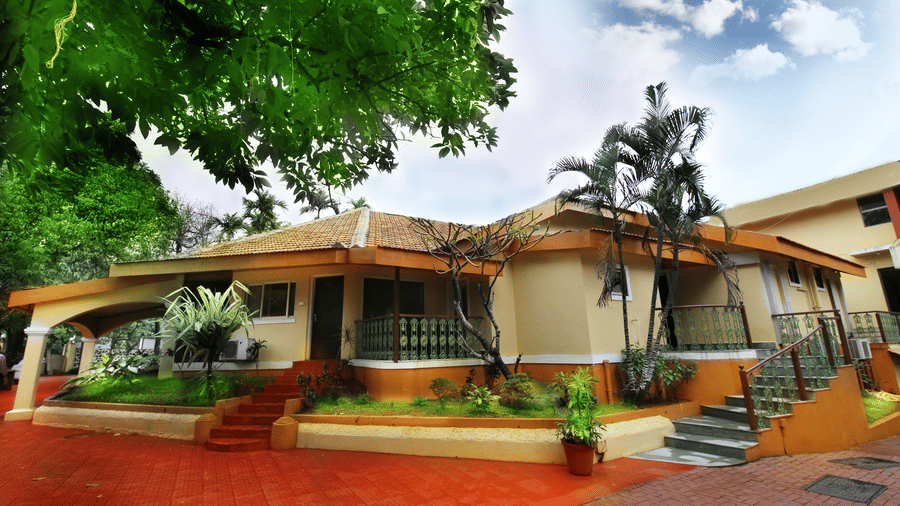 An overview of the exterior facade of the Zara's Resort, Khandala, surrounded by greenery and blue sky in the background.