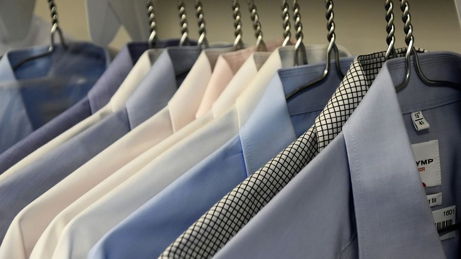 Neatly pressed, colourful dress shirts hanging on metal hangers in a wardrobe, showcasing a clean and organised laundry service.