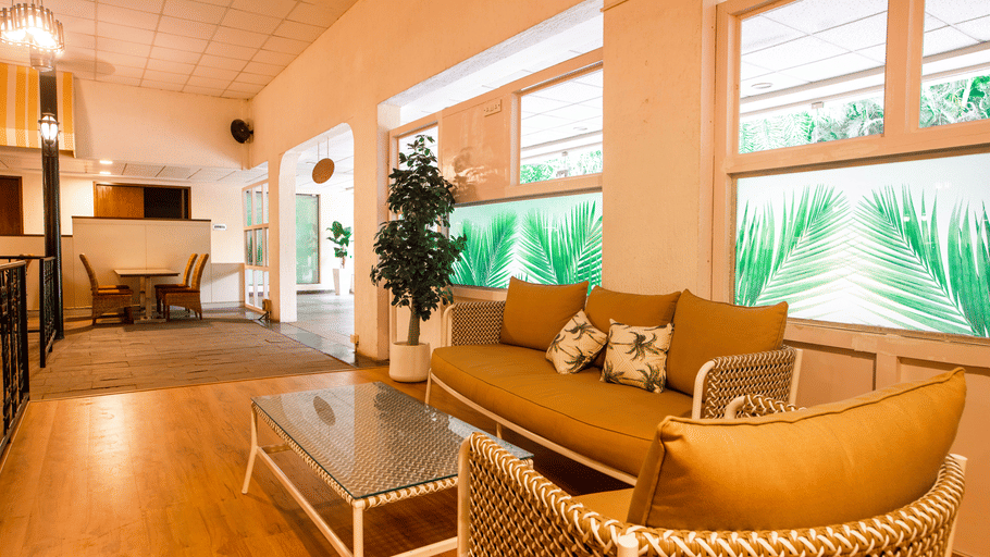 Lounge seating area at The Courtyard Restaurant, Featherlite Evoma Hotel with a wicker sofa, a coffee table and large windows nearby.