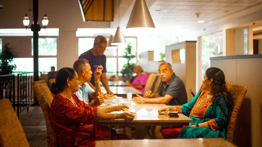 Guests seated together enjoying a meal in the warm dining space at OJ Japanese Restaurant, Featherlite Evoma Hotel.