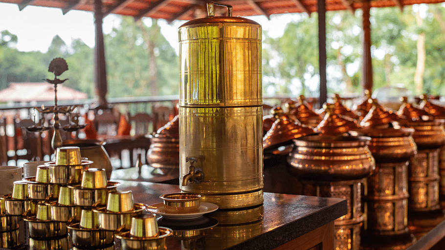 Tea pouring container with brass glasses on the side at Navarasa restaurant TGI Tapovana