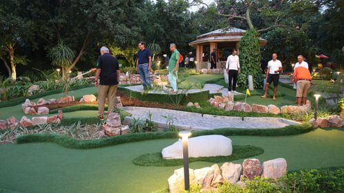 Guests enjoying mini-golf at night with well-lit pathways
