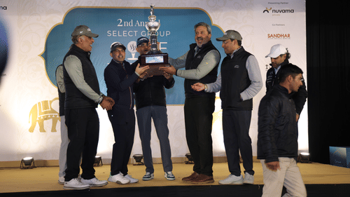 Couple of people standing on a stage holding a trophy.- Heritage Village Resorts & Spa