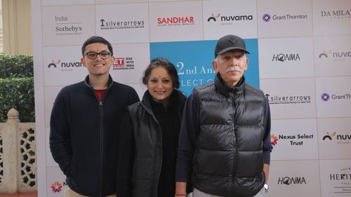 A woman and two man stand close behind a promotional background. - Heritage Village Resorts & Spa