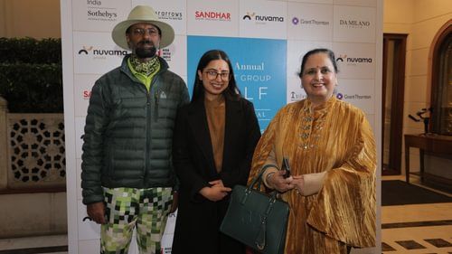 Two women and a man stand together in front of a promotional background. - Heritage Village Resorts & Spa