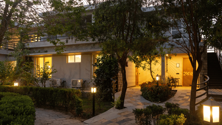 Building's exterior illuminated with warm lights, showing a pathway and garden area at The Golden Tusk, Jim Corbett